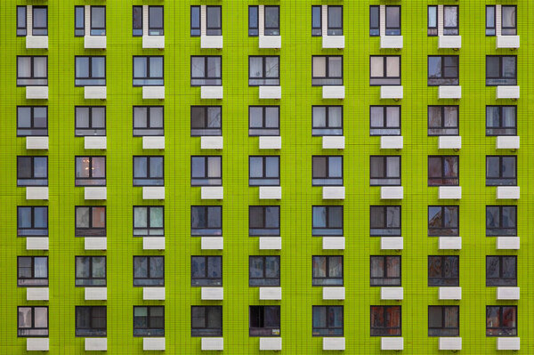 Background image - green wall of a multi-storey building with identical windows