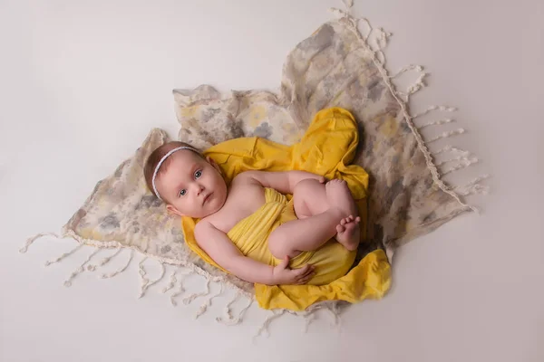 黄色の服に灰色の背景をした新生児が背中に横たわっています 幸せな子供時代 スタイリッシュな新生児や子供のための外観 — ストック写真