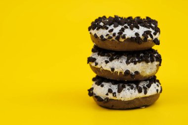 Sarı arka planda üç çikolatalı çörek, üç çikolata parçacıklı çörek, sarı arka planda.