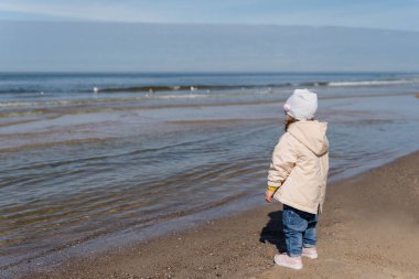 Mutlu genç aile gün batımında sahilde koşup zıplıyor. Sahilde çocuklu bir aile.