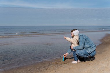 Mutlu genç aile gün batımında sahilde koşup zıplıyor. Sahilde çocuklu bir aile.