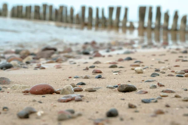Çakıl taşı plajlı deniz kıyısında güzel pembe gün batımı gökyüzü. Fotoğraf, uzun deklanşör hızı kullanılarak dondurulmuştur. Güzel deniz manzarası. Toprağın üzerinde çakıl taşları