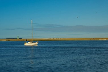 Dağın arka planına karşı denizde yüzen bir tekne. Yelkenli gemi