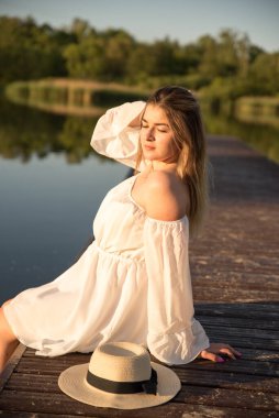 Sahilde duran şapkalı güzel bir kız. Şapka elinde..