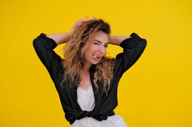 Sarı arka planda güzel bir kız. Çok cesur bir kadın vahşi yüzünü gösteriyor parmaklarıyla boğa boynuzları yapıyor..