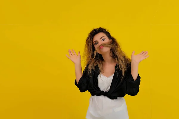 Close-up portrait of a beautiful girl on a yellow background. woman shows surprise. Shocked surprised stunned. positive human emotions