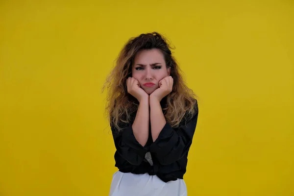 Close-up portrait of a beautiful girl on a yellow background. a woman shows that she is offended, resentment, advertises copy space