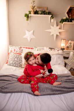 two children sit near the Christmas tree for christmas and hold gifts in their hands