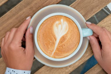 Kadın eli bir fincan kahve tutar. Bir fincan yakın çekim kahve.