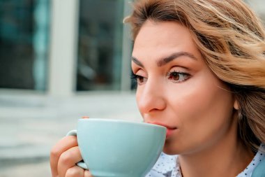 Sokakta kahve içen bir kız. Bir fincan kahve. Bir fincan kahve ve bir kızın yüzünü yakından çek..