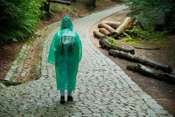 a girl tourist in a raincoat walks through the forest. forest with path.