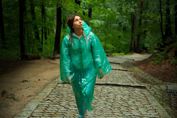 a girl tourist in a raincoat walks through the forest. forest with path.