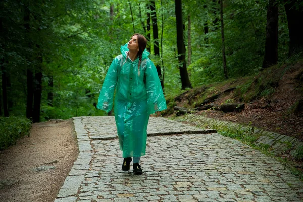 a girl tourist in a raincoat walks through the forest. forest with path.