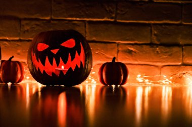 Cadılar Bayramı 'nın özellikleri. Cadılar Bayramı. Oyulmuş balkabağı. Mumlar. Duman. Karanlık sahne. kabak kafalı siluetler.