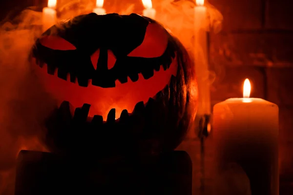 stock image Halloween's holiday attributes. Halloween. carved pumpkin. candles . smoke . dark scene. pumpkin head silhouettes.