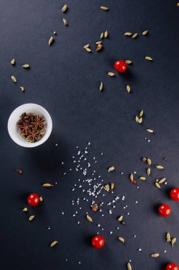 Büyük tuz, sebze, baharat, biberiye ve kiraz domateslerinin serpildiği menü için koyu arkaplan.