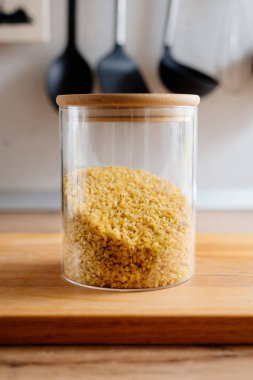 Mutfakta cam bir kavanozda bulgur. Mutfak masasındaki kavanozda bulgur ezmesi.