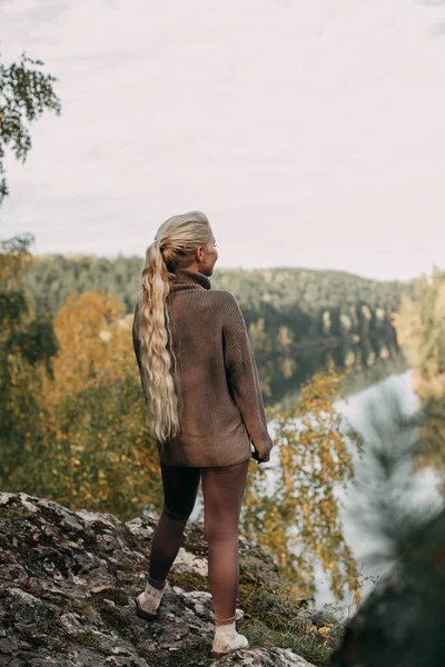 Una joven rubia camina en otoño en las montañas con vistas al río y al bosque — Foto de Stock