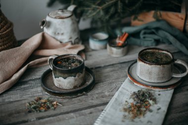 Seramik kupalar, ahşap bir masada çay.