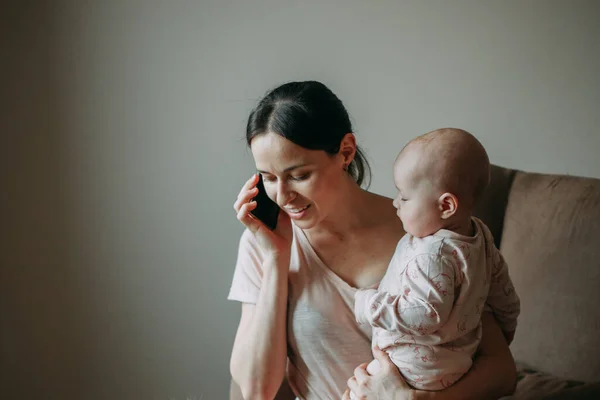 Młoda Brunetka Garniturze Siedzi Domu Fotelu Trzyma Syna Ramionach Rozmawia — Zdjęcie stockowe