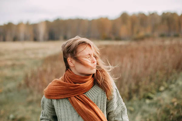 Retrato de una joven rubia en un suéter verde y jeans marrones en un campo en otoño — Foto de Stock