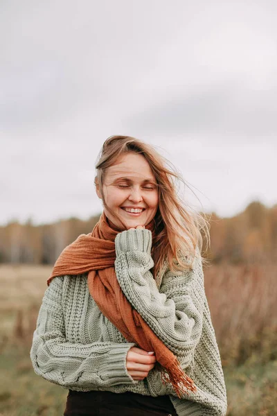 Retrato de una joven rubia en un suéter verde y jeans marrones en un campo en otoño — Foto de Stock