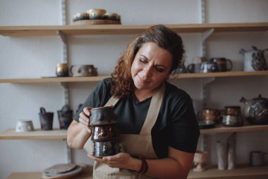 Orta yaşlı bir kadın çömlekçilik atölyesinde çevre dostu kil çatal bıçaklarıyla.