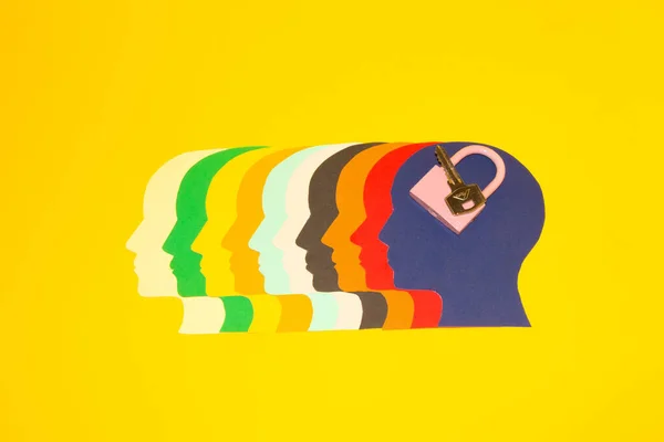 colorful paper heads facing left and the last blue head with key and padlock, security creative thinking about safe solutions, yellow background