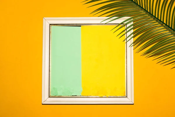frame with yellow-pastel green copy space, around the frame yellow background with palm leaf