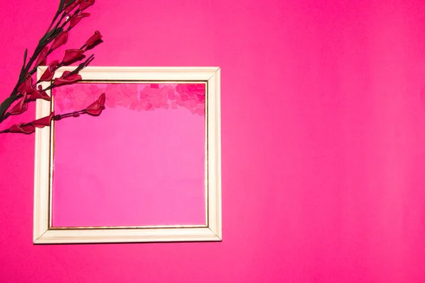 white frame on the left side of the pink background with a branch and pink flowers next to copy space, in the frame also copy space, creative art design