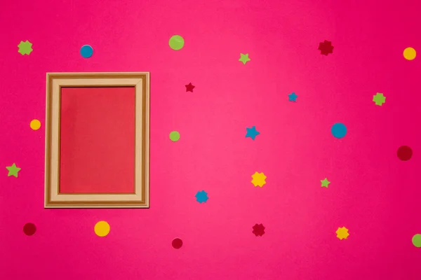 wooden retro frame with red copy space on the left pink background, colorful geometric shapes all over the background
