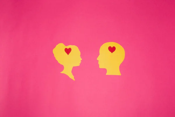 yellow paper head with heart in head, love heads looking at each other on pink background, creative art design