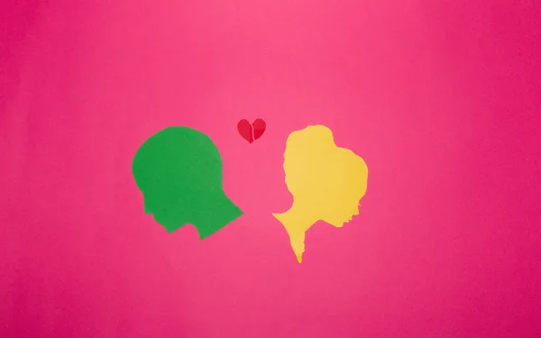 breakup, sad scene, colorful paper head have ended their relationship and are sad, pink background, two heads and torn heart between creative art design