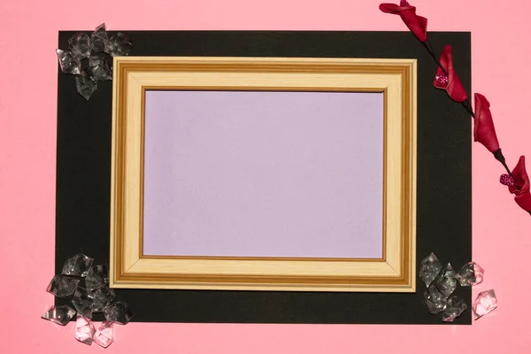 wooden old frame with purple copy space, around the frame black-pink background with flower and gems, creative luxury design