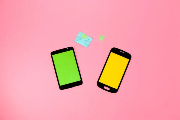 creative idea of sending love messages, two phones with a green and yellow screen as copy space, from the green comes a message in an envelope with a heart, love a combination of modern and retro ti