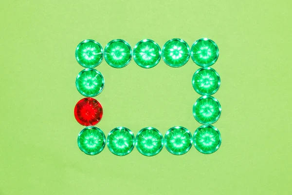 frame of green fake gemstones and one red one on a green background, frame as copy space, creative art modern design