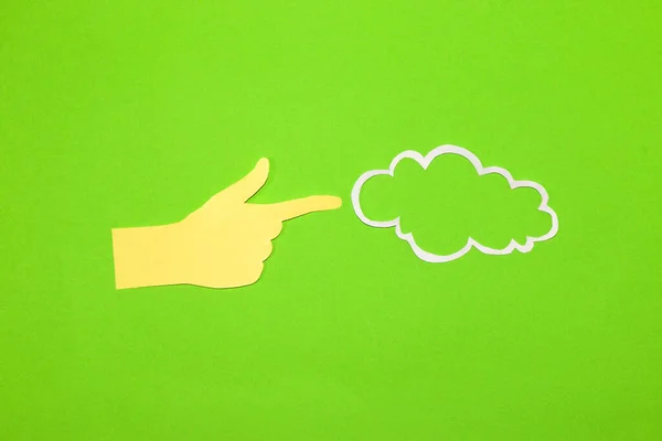 paper hand pointing to the cloud that serves as copy space, green background, eco design, creative idea
