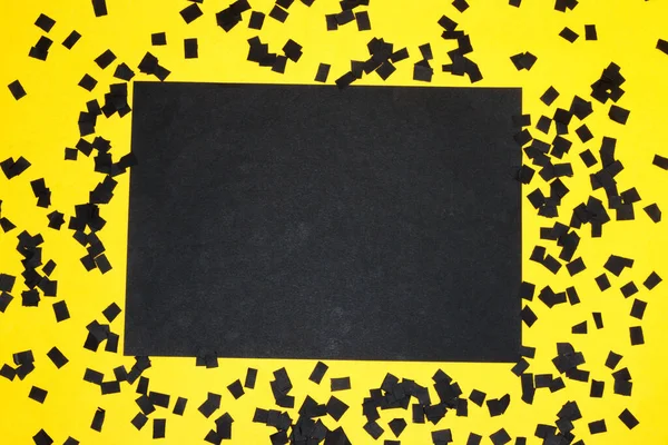 black paper as copy space on a yellow background with lots of shredded black papers, creative art design