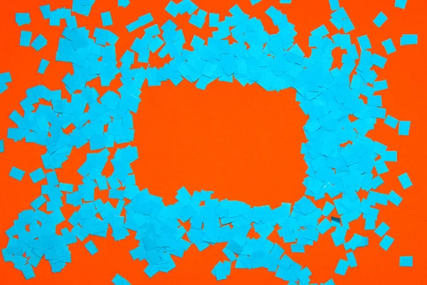 frame of shredded blue torn paper on orange background, copy space, creative design with complementary colors