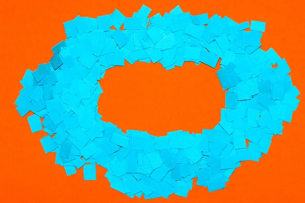 frame of chopped blue paper on orange background, copy space, creative design with complementary colors