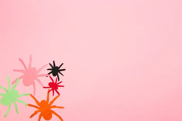 colorful paper spiders in the corner of the background, pink copy space, flat lay, paper craft, creative halloween concept