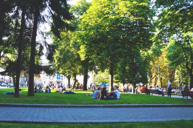 Şehir parkındaki insanlar, çimlerin üzerinde dinleniyorlar. Turistler dinleniyor.