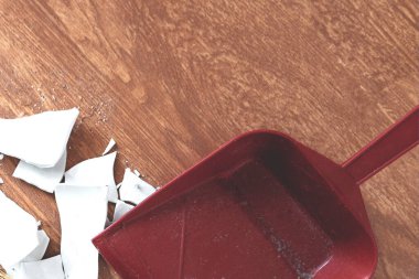 Parçalar ve faraş yerde. Kırık bir tabağın kepçesi ve kırıkları. Üst görünüm. Ev temizliği, kriz ve sorun kavramı.