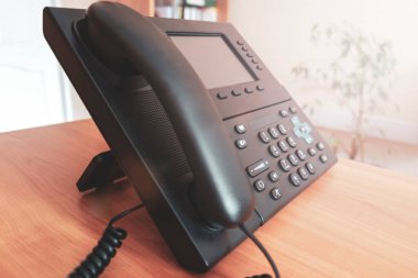 Siyah masaüstü tuşlu telefon. Ofisteki masada IP telefonu var. İletişim konsepti. yakın plan