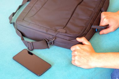 Akıllı telefon ve laptop çantası. El dizüstü bilgisayar çantasını alır.
