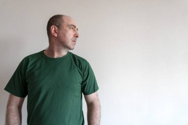 Adam giyiniyor, tişört deniyor. Tişört ve kot giyen adam ayakta duruyor. Kıyafet denemenin konsepti. Boşluğu kopyala