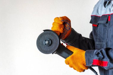 İşçi bir disk ile öğütme makinesi tutuyor. Boşluğu kopyala