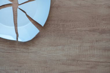 Arka planda kırık bir tabağın parçaları var. Parçalanmış bir tabağın kıymıkları. Yerdeki bir sofra takımının parçaları. Mutfak eşyalarının parçaları ve enkazı, boşluğu kopyala