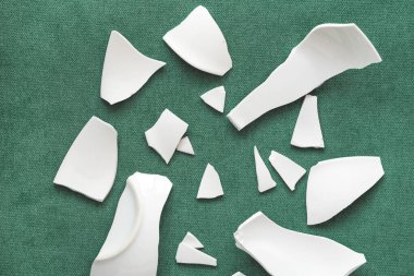 Kırık beyaz kapların kıymıkları ve parçaları. Bir aile kavgasının metaforu. Kırık tabak, cam. Mutfaktaki kaza kavramı. Parçalanmış tabak parçaları.. 