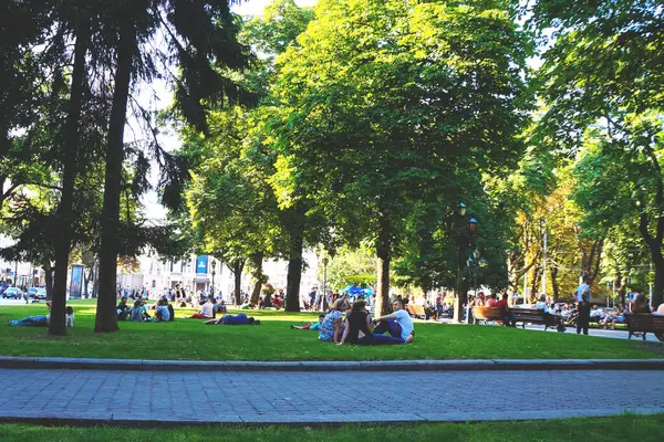 Şehir parkındaki insanlar, çimlerin üzerinde dinleniyorlar. Turistler dinleniyor.